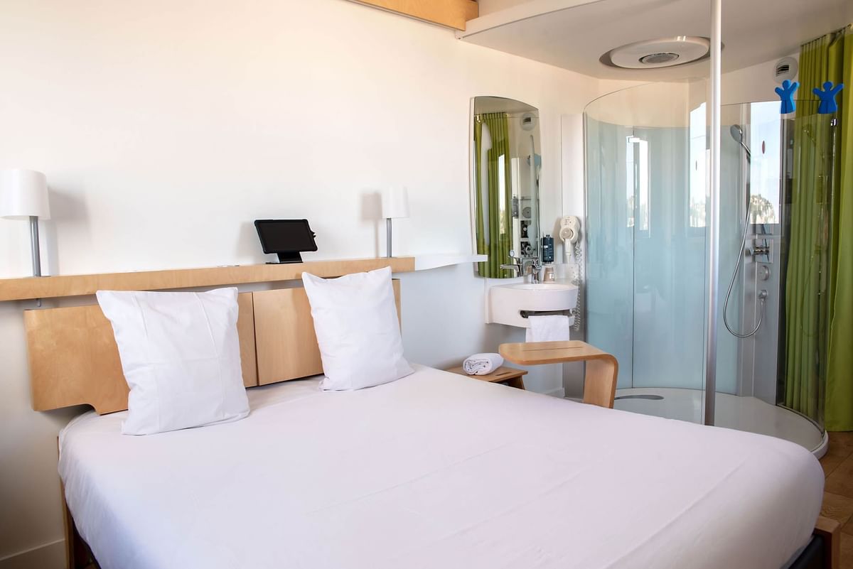 Lit confortable avec une zone de douche au Nomad Hotels