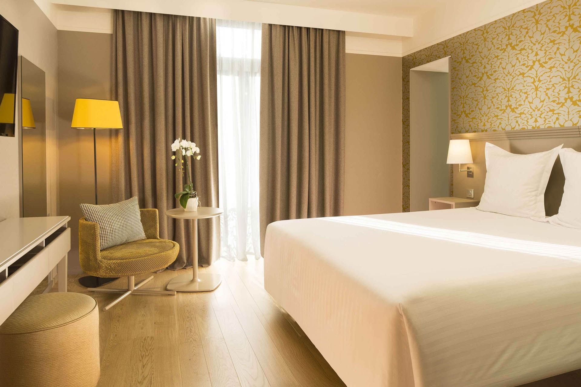 Comfy bed and chair in a hotel room at Oceania Hotels