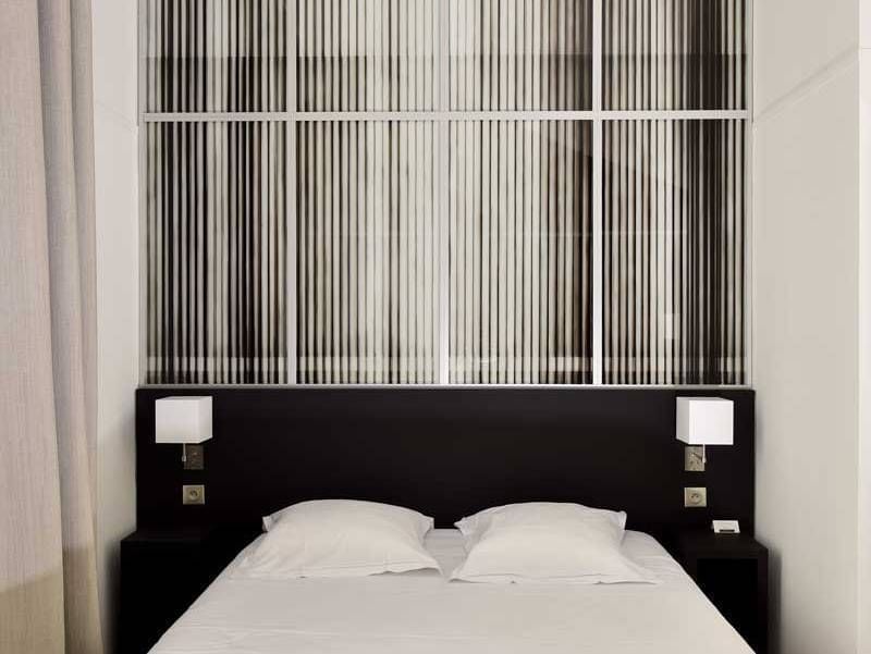 Lit confortable avec tables de chevet dans une chambre aux Oceania Hotels