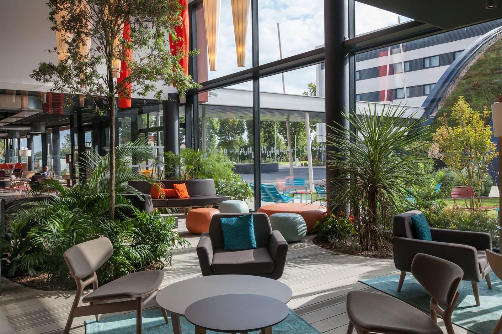 The elegant lobby area with comfy sofas and chairs arranged at Nomad Hotels Paris Roissy